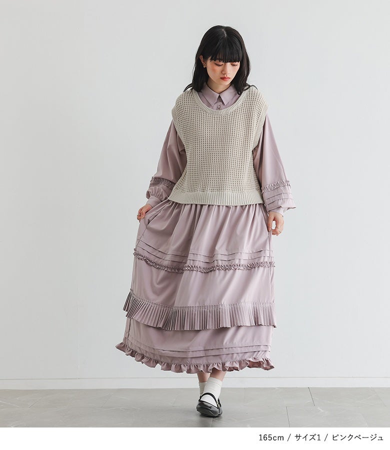 ピンクベージュのニットベスト重ね風ドッキングワンピース。あたたかみのあるくすみカラーとフリルを重ねたティアードデザインが、可憐で優雅な装いへと導きます。