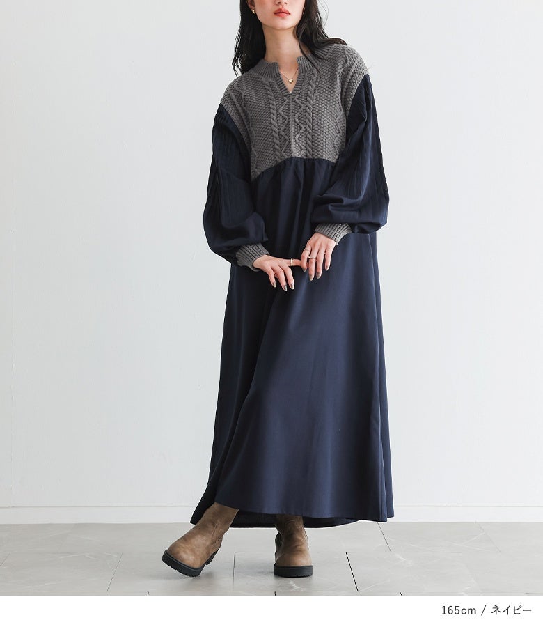 ネイビーのロングワンピースにグレーのケーブルニット切替とブーツを合わせた上品なレディース秋コーデ。袖に施したプリーツデザインが歩くたびにエレガントな表情を魅せます。