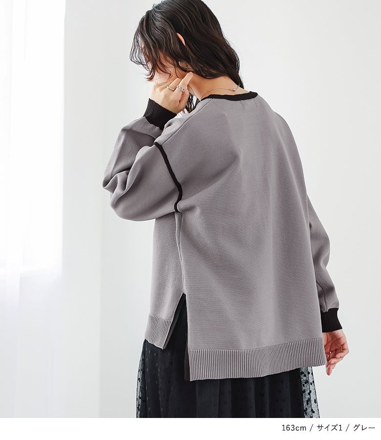 黒のパイピングラインとサイドスリットが印象的なグレーの長袖ニットトップス。ドット柄チュールワンピースとのレイヤードでこなれた後ろ姿を演出する上品な着こなしです。