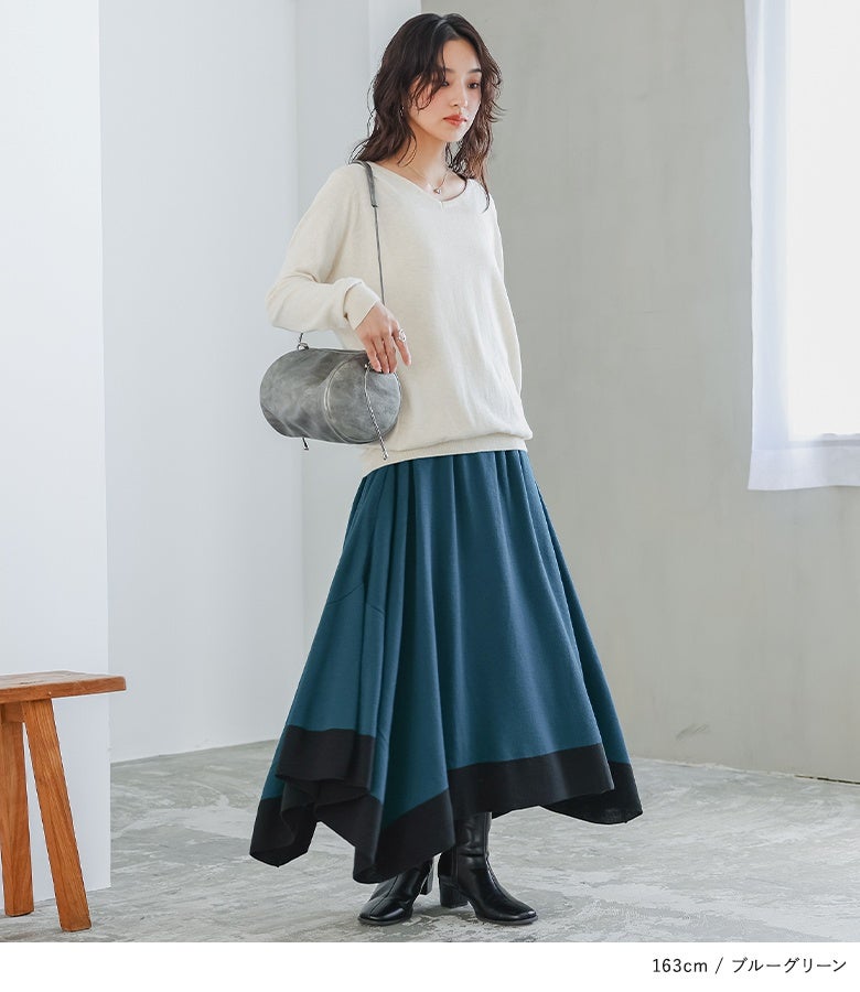 ブルーグリーンの変形アシメニットスカート。深みのあるアースカラーと落ち感のあるロングシルエットが、上品でこなれた大人の休日スタイルを完成させます。