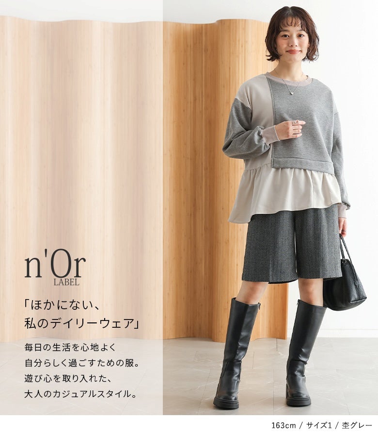 杢グレーの異素材切り替え裏起毛スウェット。ショートパンツとロングブーツを合わせたモードカジュアルなスタイルに、裾フリルの軽やかさが上品にマッチします。